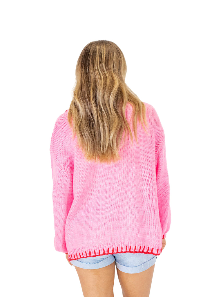 pink cardigan with red stitching and white bows